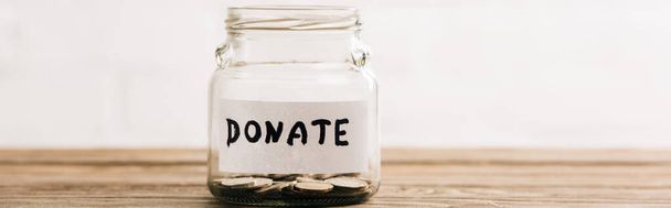 penny jar with donate lettering on wooden surface on white background, panoramic shot - Foto, immagini