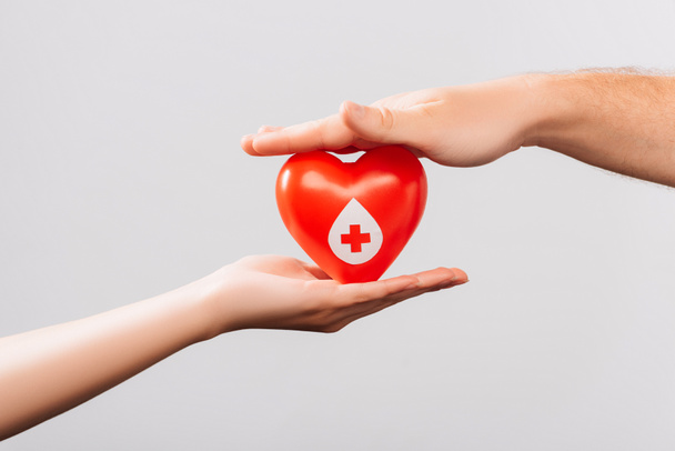vista recortada de hombres y mujeres con corazón rojo aislado en blanco, concepto de donación de sangre - Foto, imagen