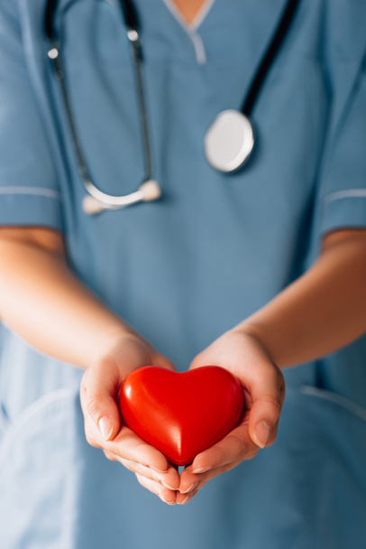 cropped view of doctor with stereoscope holding red heart - Fotografie, Obrázek
