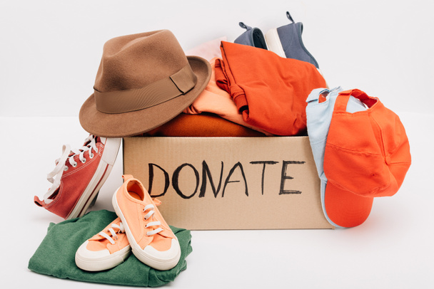 pudełko tekturowe z darowanymi akcesoriami, ubraniami i obuwiem odizolowane od białej, charytatywnej koncepcji - Zdjęcie, obraz