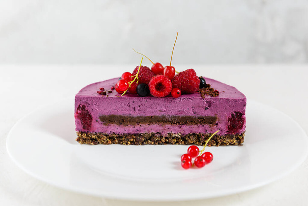 Mousse cashew cake with black currant and chocolate praline in a cut. Sugar, lactose, gluten free. Vegan dessert, healthy food. - Photo, Image