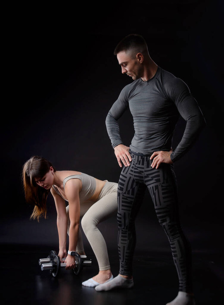 a man and a woman are engaged in sports in the hands of dumbbells - Zdjęcie, obraz