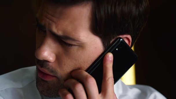 ビジネスマンはオフィスでスマートフォンで話している。従業員の携帯電話への通話 - 写真・画像