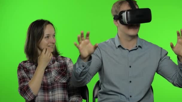 Hombre y mujer usando casco de auriculares VR para jugar. Ver vídeo en 3D de realidad virtual. Clave de croma - Imágenes, Vídeo