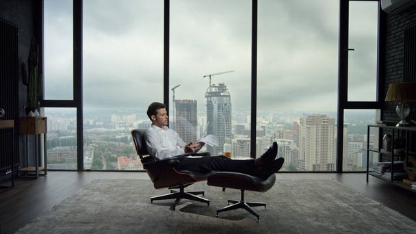 Biznesmen przegląda dokumenty biznesowe w biurze. Pracownik siedzący na krześle - Zdjęcie, obraz