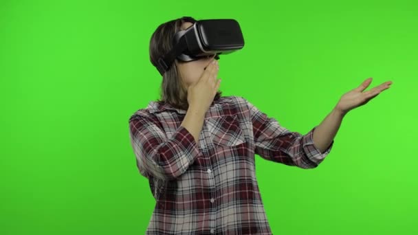 Mujer joven que usa casco de auriculares VR para jugar, mostrando el área de publicidad lateral. Clave de croma - Imágenes, Vídeo