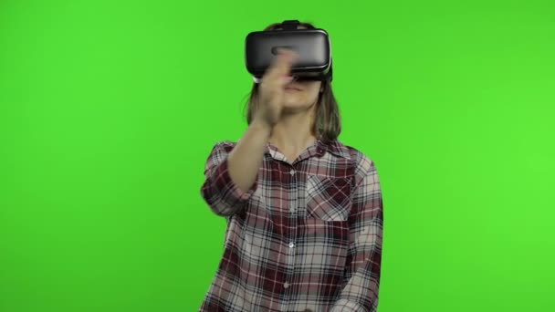 Chica usando casco de aplicación VR para jugar juego de simulación. Gestos de diapositivas. Viendo la realidad virtual 3d video - Metraje, vídeo