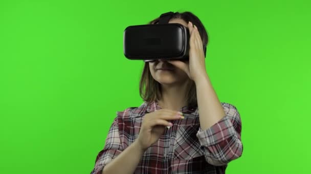 Chica usando casco de aplicación VR para jugar juego de simulación. Gestos de diapositivas. Viendo la realidad virtual 3d video - Metraje, vídeo