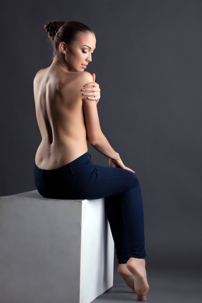 Pretty slim woman posing topless sitting on cube - Фото, зображення