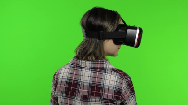 Chica joven usando casco de aplicación VR para jugar juego de simulación. Mujer viendo realidad virtual 3d video - Imágenes, Vídeo