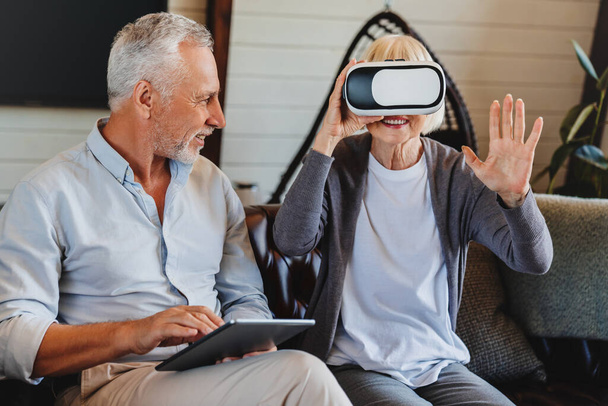 Old elderly retired woman using VR virtual reality headset in apartment. - Foto, Imagen