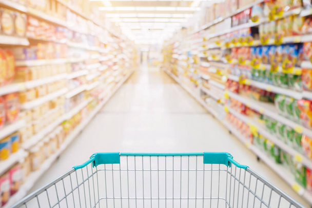 Warenkorbansicht im Gang des Supermarktes mit Produktregalen abstrakte Unschärfe defokussierten Hintergrund - Foto, Bild