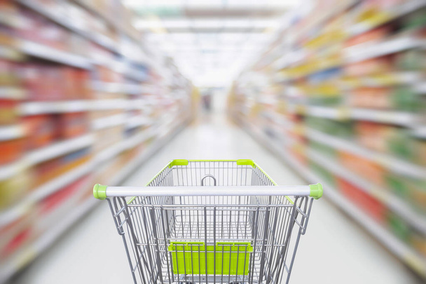 Проход супермаркета с пустой зеленой тележкой в движении - Фото, изображение