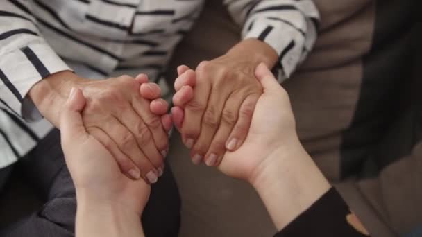 Κοντινό πλάνο, νεαρή γυναίκα και ηλικιωμένη γυναίκα κρατιούνται χέρι-χέρι. Οικογενειακή έννοια δεσίματος - Πλάνα, βίντεο
