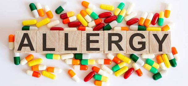 Puiset kuutiot kirjoitus allergia eristetty harmaalla pohjalla lääketieteellisiä kapseleita. - Valokuva, kuva