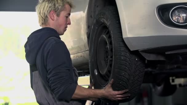 Mecánico fija el neumático de nuevo a su lugar
 - Metraje, vídeo