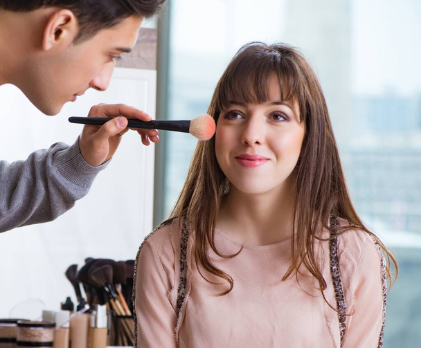 Man doing make-up for cute woman in beauty salon - Foto, Imagen