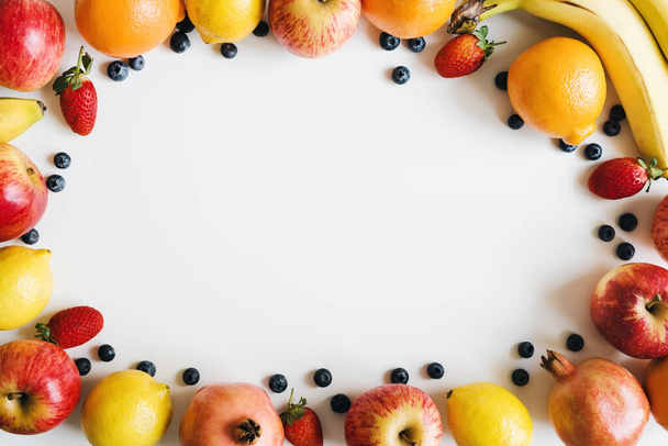 Vlak gelegd met vers fruit en bessen op witte achtergrond. Voedselframe. Plantaardige voeding - Foto, afbeelding