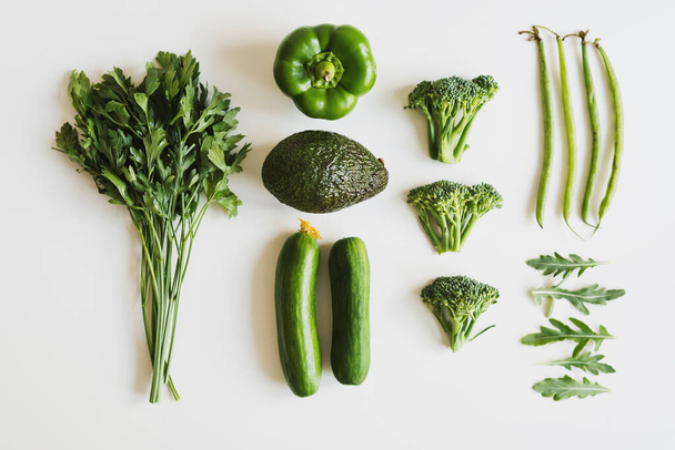 Food layout with parsley, bell pepper, avocado, cucumber, broccoli florets, green beans and arugula leaves. Green vegetables flat lay. Alkaline food - 写真・画像