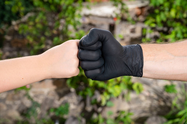apretón de manos, saludo con guantes médicos protectores. Protección contra el coronavirus - Foto, imagen