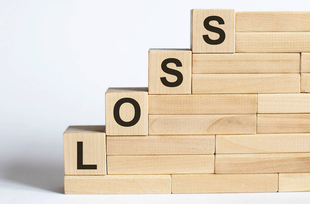 Trzy drewniane kostki z literami LOSS na białym stole. Biznes - Zdjęcie, obraz