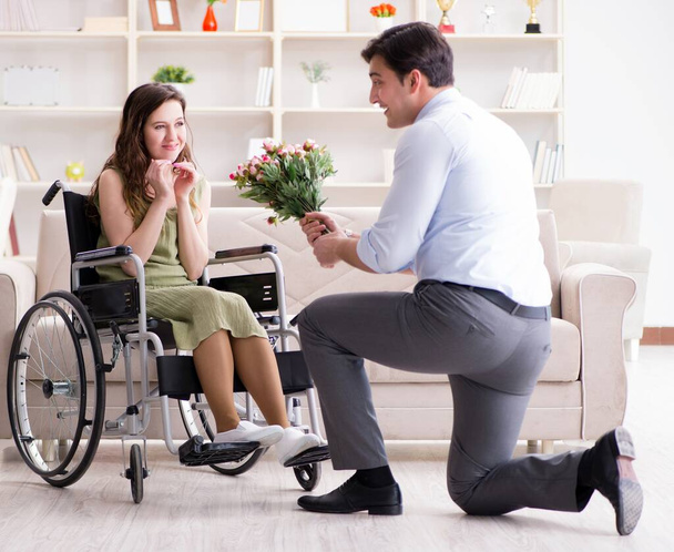 車椅子の障害者女性と結婚の提案をする男 - 写真・画像
