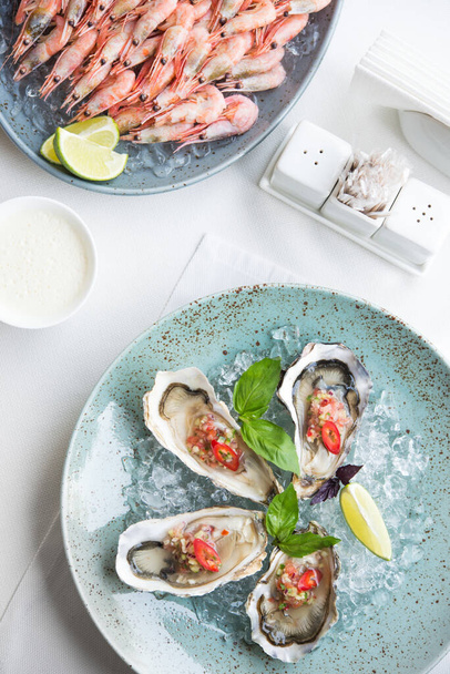 Zeevruchten voor twee, diner in het restaurant, oesters en garnalen op tafel. bovenaanzicht - Foto, afbeelding