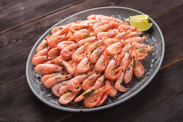 Tasty shrimp with lime on a brown wooden table. Seafood dinner. - Foto, afbeelding