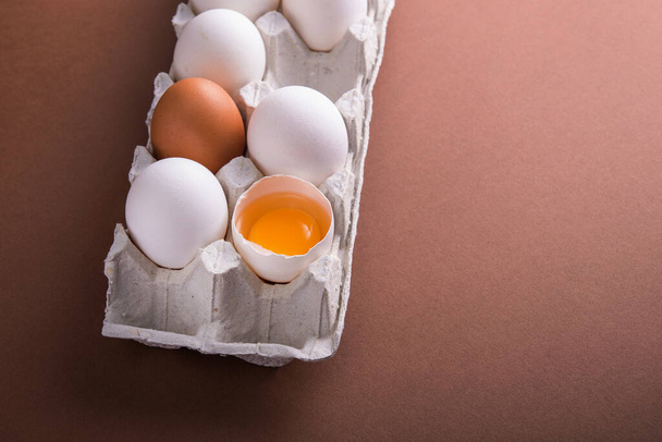茶色のテーブルの上に生の白い卵のトレイ。朝食の準備 - 写真・画像