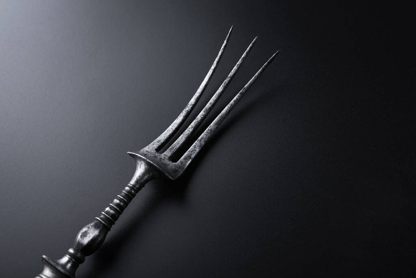 Metal vintage fork for meat steak on a black background - Foto, afbeelding