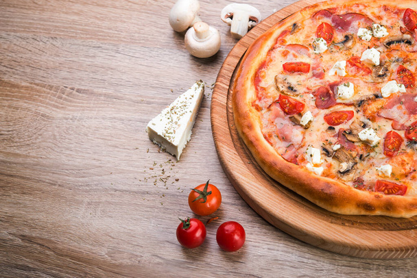 Pizza italienne chaude avec bacon, champignons et fromage sur planche de bois.  - Photo, image