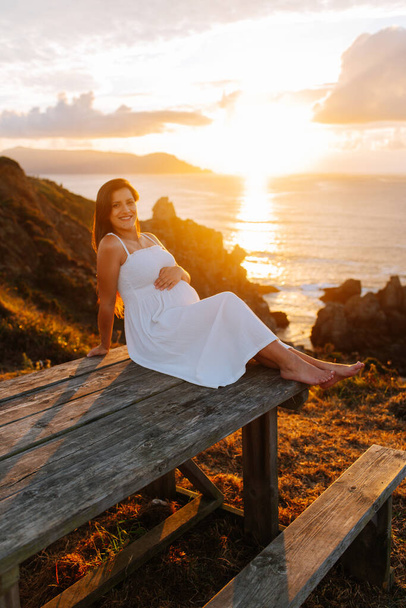 Pregnant woman against an oceanic landscape at sunset in Galicia, Spain - Photo, Image