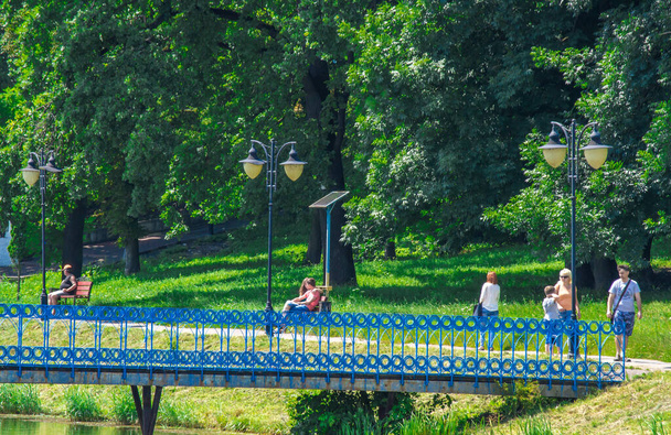 Ukraina, Kalush, sierpień 2020: Krajobraz parku miejskiego. Ludzie relaksują się spacerując w niedzielny letni dzień wśród zieleni oddychając świeżym powietrzem wzbogaconym tlenem z drzew - Zdjęcie, obraz