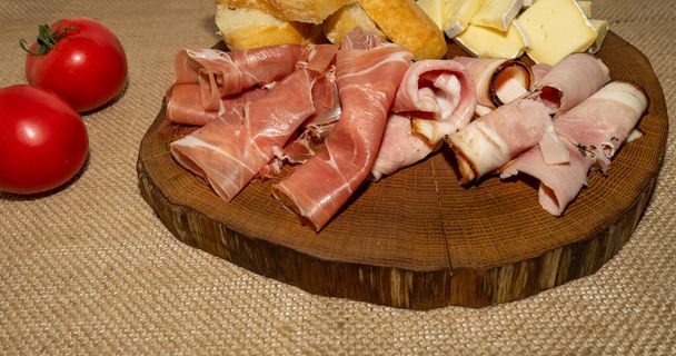 Wine appetizer. Ham, Parma ham, baguette, Cheese on a wooden stand - Photo, Image