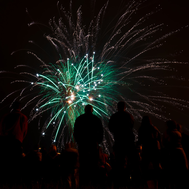 Grandes fuegos artificiales con siluetas de gente mirándolo
 - Foto, imagen