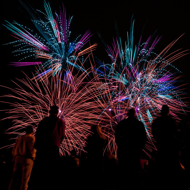 Grandi fuochi d'artificio con sagome di persone che lo guardano
 - Foto, immagini