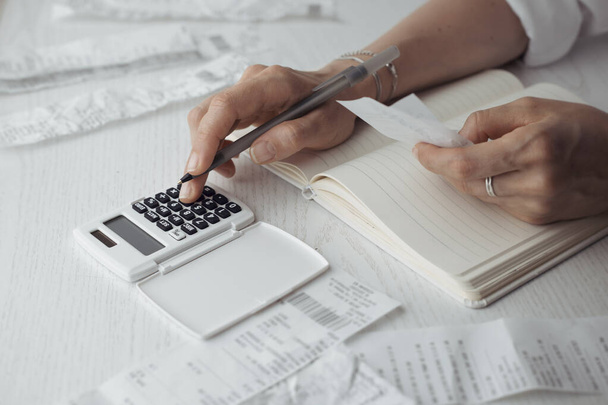 La persona cuenta las facturas pagadas en la calculadora. Contabilidad casera. - Foto, Imagen