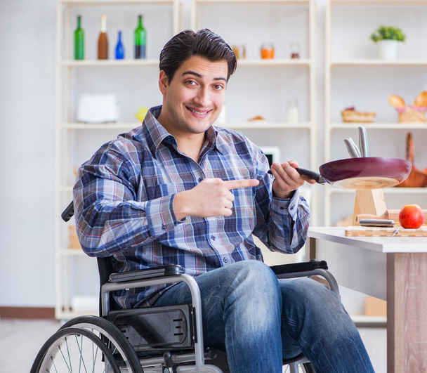 Ο ανάπηρος νεαρός σύζυγος τηγανίζεται στην κουζίνα - Φωτογραφία, εικόνα