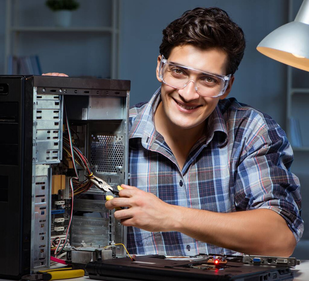 Чоловік ремонтує комп'ютерну стільницю з плоскогубцями
 - Фото, зображення