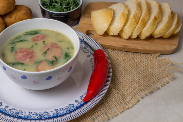 Caldo Verde Soup) - популярний суп в португальській кухні з зеленим і нарізаним хорізо на вершині керамічної чаші і шматком хліба і перцю. Вид зверху - Фото, зображення