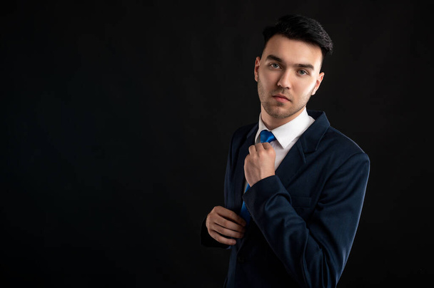 Πορτρέτο του επιχειρηματία τακτοποίηση γραβάτα του απομονώνονται σε μαύρο φόντο με αντίγραφο χώρο διαφήμισης - Φωτογραφία, εικόνα