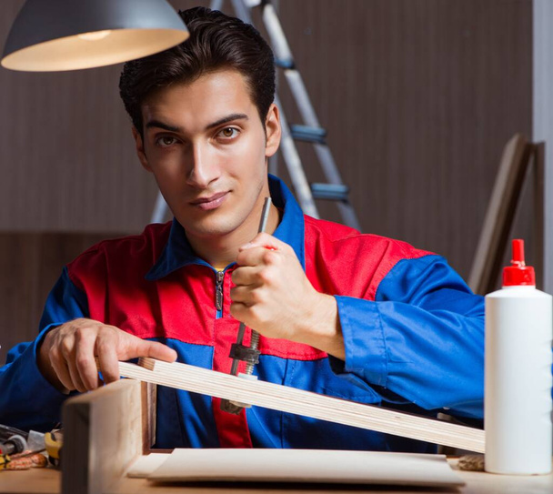 Junger Mann klebt Holzteile in DIY-Konzept zusammen - Foto, Bild