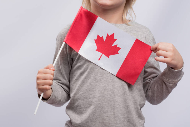 Το παιδί κρατάει τη σημαία του Καναδά. Κλείσε. Μετανάστευση στον Καναδά. Εκπαίδευση στον Καναδά για παιδιά - Φωτογραφία, εικόνα