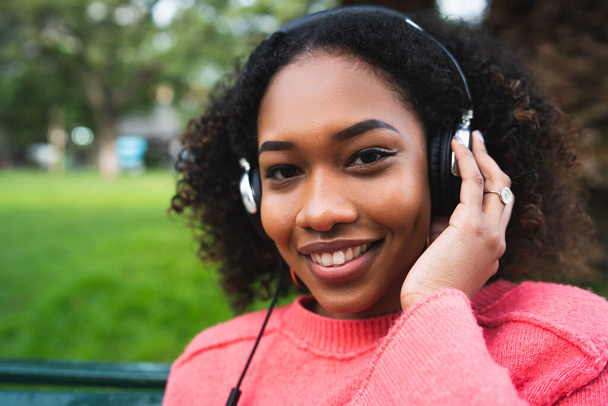 Portrait of Afro american woman smiling and listening to music with headphones in the park. Outdoors. - Φωτογραφία, εικόνα