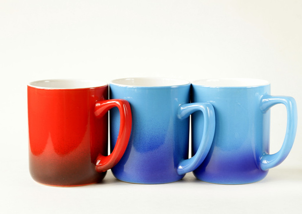 Три красочные кружки кофе (синий, красный) на белом фоне
 - Фото, изображение