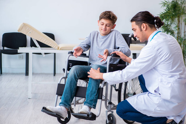 junger Arzt Kinderarzt und Junge im Rollstuhl - Foto, Bild