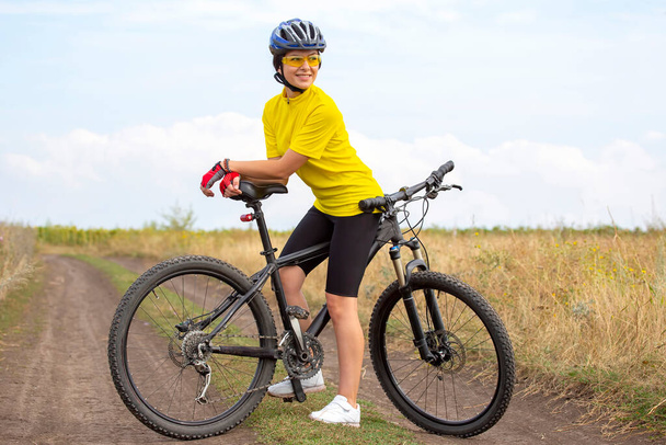 Bela e feliz menina ciclista com uma bicicleta na natureza. Estilo de vida saudável e esportes. Lazer e hobbies - Foto, Imagem