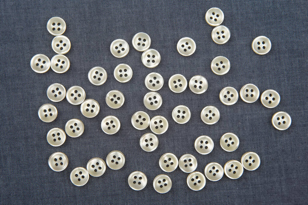 Plastic shiny buttons for clothes on a fabric background. Fashion and clothing. Factory industry - Photo, Image