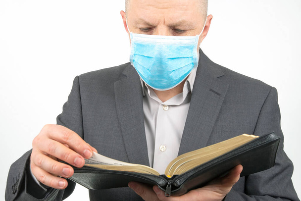 Mann in medizinischer Maske studiert die Bibel. Religion und Christentum. - Foto, Bild
