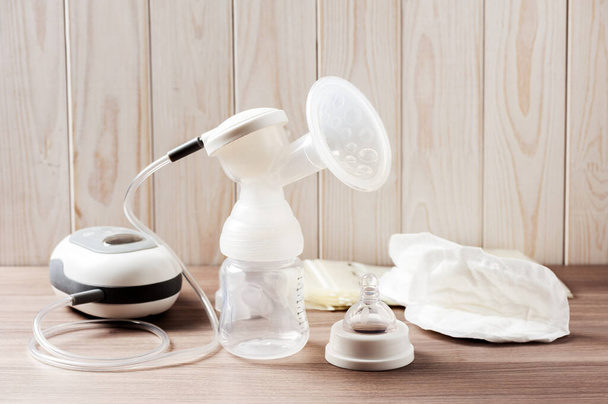 Breast pump and blank baby bottle on wood background - Photo, Image